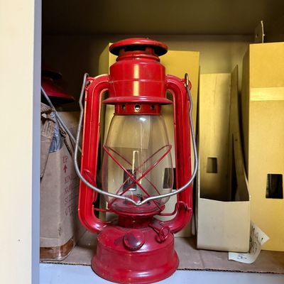 Sale Photo Thumbnail #80: Vintage bright red metal tubular kerosene lantern with a wire handle and clear glass globe.