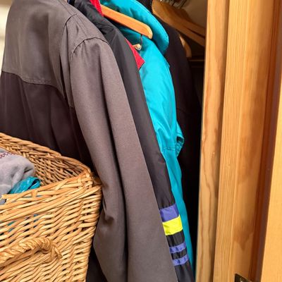 Sale Photo Thumbnail #4: Assorted men's and women's winter coats and jackets hanging in a closet next to a woven wicker basket.
