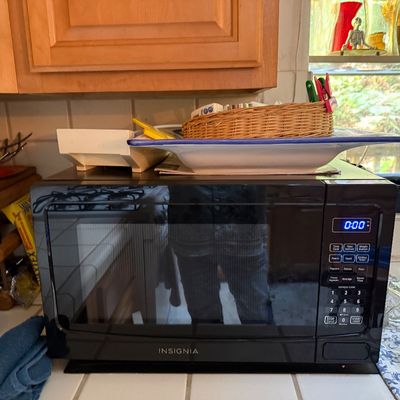 Sale Photo Thumbnail #30: Insignia countertop microwave oven in black finish, positioned on a tiled kitchen counter.