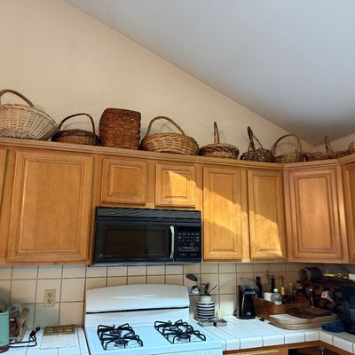 Sale Photo Thumbnail #28: Collection of rustic woven baskets display arranged above modern oak kitchen cabinets.