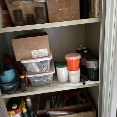 Sale Photo Thumbnail #82: Metal storage cabinet packed with various garage supplies, hardware, paint cans, plastic containers, and small power tools.