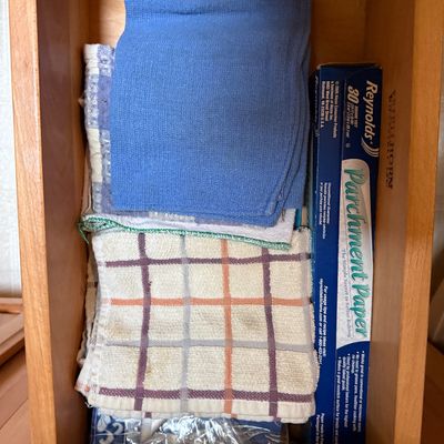 Sale Photo Thumbnail #48: Wooden kitchen drawer filled with folded kitchen towels, dishcloths, and a box of Reynolds parchment paper.