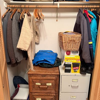 Sale Photo Thumbnail #2: Bedroom closet filled with men's jackets, outerwear, clothing, wooden coat hangers, a wicker basket, and two two-drawer filing cabinets.