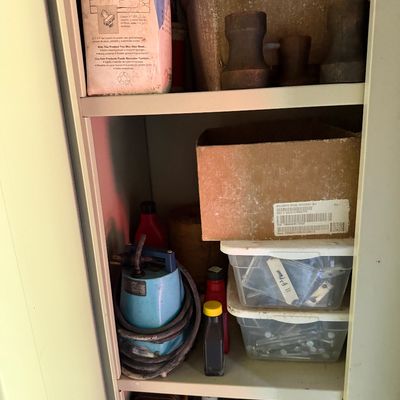 Sale Photo Thumbnail #81: Metal storage cabinet filled with assorted hardware, a small submersible utility pump, cleaning supplies, and cardboard boxes.