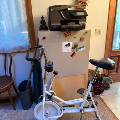 Sale Photo Thumbnail #10: Vintage Bodyguard white stationary exercise bike positioned in front of a metal filing cabinet topped with an HP printer.