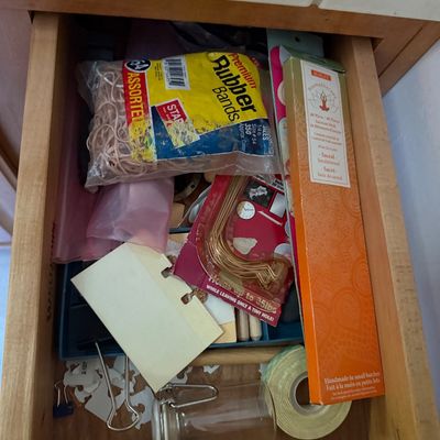 Sale Photo Thumbnail #54: Open wooden drawer filled with assorted household supplies, including a bag of rubber bands, a box of incense sticks, picture hangers, tape, and binder clips.