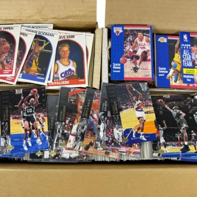 Sale Photo Thumbnail #5: Large collection of 1980s and 1990s NBA trading cards stored in cardboard boxes, including notable players like Scottie Pippen, Dennis Rodman, and Charles Barkley from Fleer, Hoops, and Upper Deck sets.