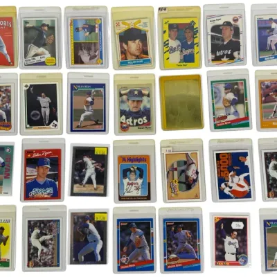 Sale Photo Thumbnail #16: Collection of vintage Nolan Ryan baseball trading cards, spanning various brands including Topps, Fleer, Donruss, and Score from the 1970s through the 1990s, all individually housed in protective top-loader sleeves.