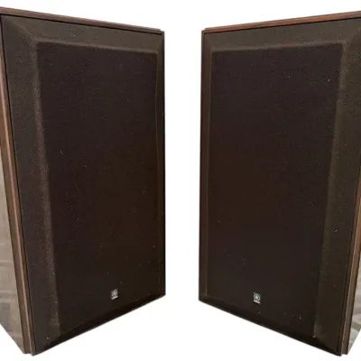Sale Photo Thumbnail #3: Pair of vintage Yamaha stereo speakers featuring woodgrain cabinets and dark brown cloth speaker grilles with small logo badges.