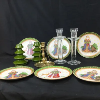 Sale Photo Thumbnail #14: Collection of holiday table decor including Fitz and Floyd Russian Santa plates, clear glass taper candle holders, green ceramic tree holders, and a brass chamberstick.