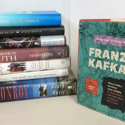 Sale Photo Thumbnail #100: Collection of modern hardcover books stacked alongside a vintage Modern Library paperback edition of Selected Stories of Franz Kafka.