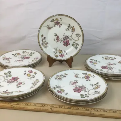 Sale Photo Thumbnail #113: Set of floral pattern porcelain salad or dessert plates featuring pink and yellow botanical motifs with a decorative border, displayed alongside wooden yardsticks for scale.