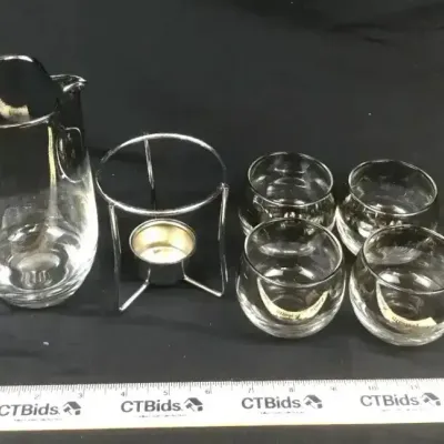Sale Photo Thumbnail #73: Vintage clear glass beverage set featuring a pitcher, four matching glasses, and a wire metal warming stand.
