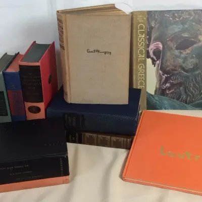 Sale Photo Thumbnail #90: Collection of vintage hardcover books, featuring titles such as 'Classical Greece,' an Ernest Hemingway volume, and an orange 'Lautrec' art book.