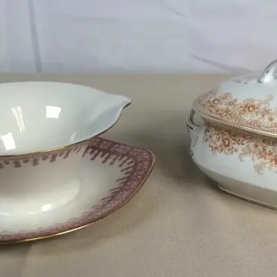 Sale Photo Thumbnail #43: Vintage porcelain gravy boat with an attached underplate and a covered vegetable tureen, both featuring floral scroll borders and gilded accents.