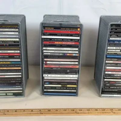 Sale Photo Thumbnail #62: Set of three wire mesh storage drawers filled with assorted compact discs, displayed alongside a wooden yardstick for scale.