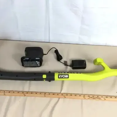 Sale Photo Thumbnail #72: Ryobi cordless string trimmer with battery pack and charger, shown alongside a yardstick for scale.