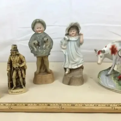 Sale Photo Thumbnail #67: Collection of vintage porcelain and resin figurines, including storybook characters, children, and a milkmaid with a cow.