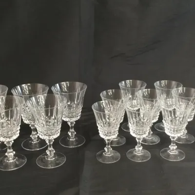 Sale Photo Thumbnail #25: Large collection of cut crystal stemware featuring intricate diamond and vertical cuts on the bowls, presented on a dark backdrop.