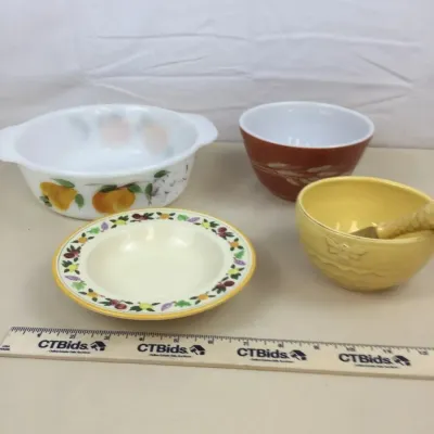Sale Photo Thumbnail #48: Assorted vintage kitchenware including Pyrex and glass bowls with fruit and wheat motifs, accompanied by a small yellow ceramic bowl with a spreader.