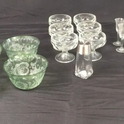 Sale Photo Thumbnail #12: Collection of vintage glassware, including green etched depression glass dessert bowls, clear sherbet coupe dishes, cordials, and small salt and pepper shakers.
