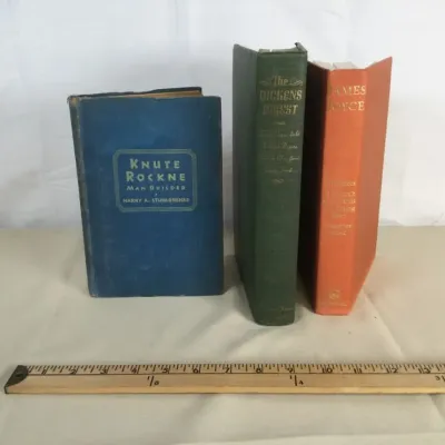 Sale Photo Thumbnail #89: Collection of three vintage hardcover books, including Knute Rockne Man Builder, The Dickens Digest, and a James Joyce compilation, showing minor shelf wear.