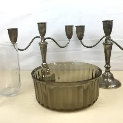 Sale Photo Thumbnail #45: Collection of tabletop items including a pair of silver-plated three-light candelabras, a smoked glass ribbed bowl, and two clear glass tumblers.