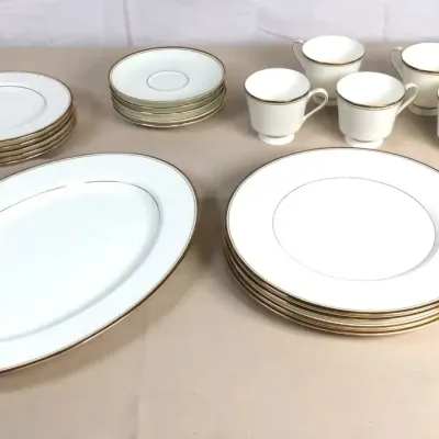 Sale Photo Thumbnail #60: Set of fine white china dinnerware featuring gold trim, including dinner plates, salad plates, saucers, teacups, and a large oval serving platter.