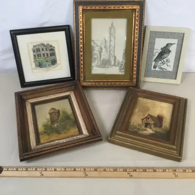 Sale Photo Thumbnail #108: Collection of five small framed artworks, including architectural sketches, rustic landscape paintings, and a bird print, shown with a yardstick for scale.