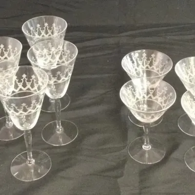 Sale Photo Thumbnail #50: Nine-piece vintage etched glassware set featuring five wine glasses and four cocktail coupe glasses with intricate crown-like scroll patterns.