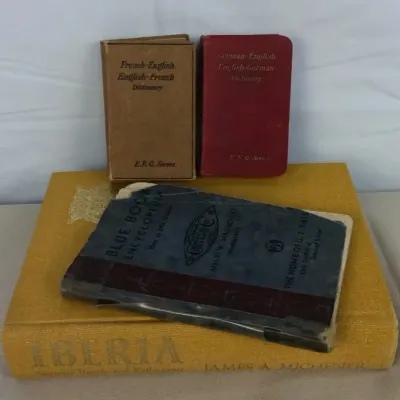 Sale Photo Thumbnail #104: Collection of vintage books including two E.F.G. Series foreign language dictionaries, a worn Blue Book Encyclopedia booklet, and a yellow clothbound copy of Iberia by James A. Michener.