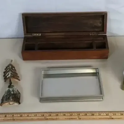 Sale Photo Thumbnail #94: Collection of decorative tabletop items, including a long wooden box, a small insect house, carved wooden figurines, and a silver-tone framed mirror or tray.