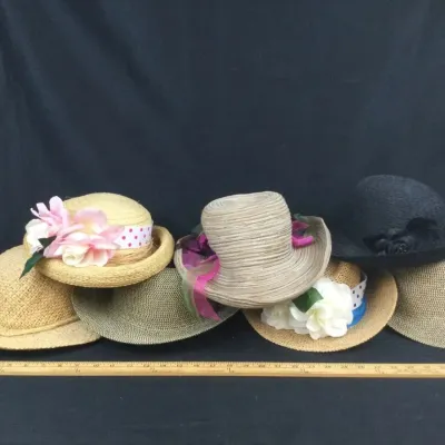 Sale Photo Thumbnail #85: Collection of seven women's straw hats and sun hats featuring floral embellishments, ribbons, and varied brim styles, displayed alongside a yardstick for scale.