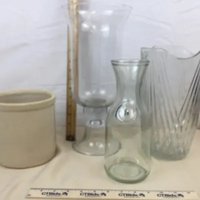 Sale Photo Thumbnail #86: Collection of glass vessels and a ceramic crock, including a large clear hurricane vase, a cut crystal vase, and a glass carafe.