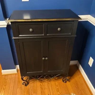 Black Two-Door Cabinet with Ornate Wrought Iron Stand