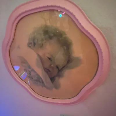 Sale Photo Thumbnail #84: Vintage framed portrait print of a sleeping child, set under bubble glass in an irregularly shaped pink frame.