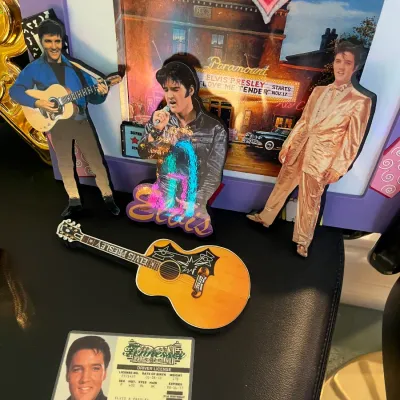 Sale Photo Thumbnail #152: Collection of Elvis Presley memorabilia including cutouts, a miniature guitar ornament, novelty Tennessee driver's license, and framed photo.