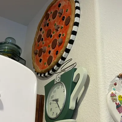 Sale Photo Thumbnail #60: Whimsical pizza-themed wall art with a black-and-white striped rim, hanging above a green teacup-shaped wall clock.
