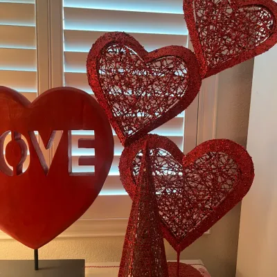 Sale Photo Thumbnail #226: Assortment of red Valentine's Day decorations, including a wooden heart sculpture reading 'LOVE' and glittered mesh heart table ornaments.