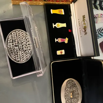 Sale Photo Thumbnail #54: Collection of boxed memorabilia and belt buckles, including a vintage 1987 Golden Nugget Country Western Jamboree buckle and a boxed Hard Rock Cafe enamel pin set.