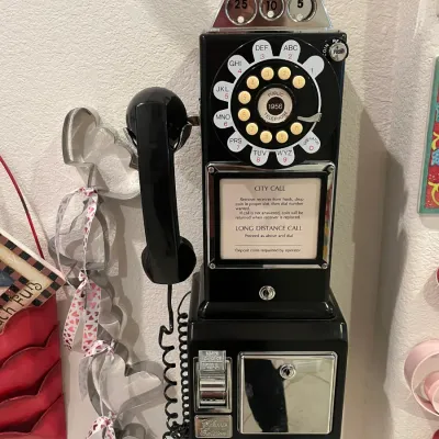 Sale Photo Thumbnail #63: Vintage-style black wall-mounted pay phone replica with a rotary dial and coin slots.