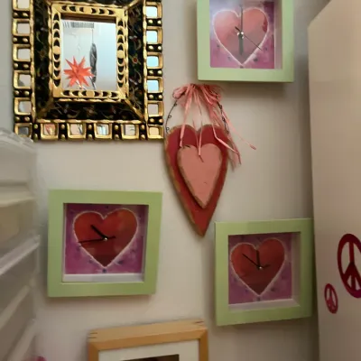 Sale Photo Thumbnail #228: Collection of heart-themed wall decor, including three matching mint green framed clocks, a painted folk art wooden heart hanging, and an ornate gilt-framed mirror.