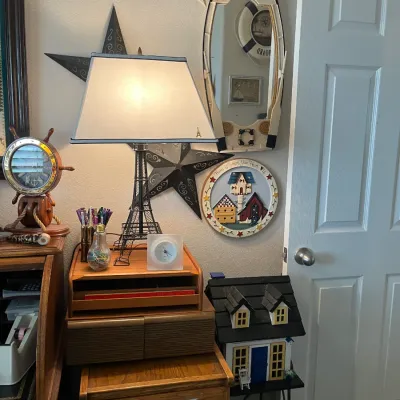 Sale Photo Thumbnail #199: Eiffel Tower-style metal desk lamp paired with various nautical and rustic decor items, including a boat-shaped mirror and a decorative miniature house.