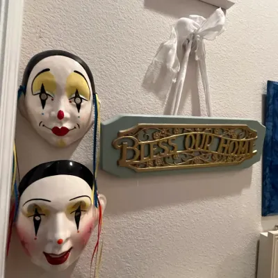 Sale Photo Thumbnail #70: Pair of ceramic harlequin clown wall masks alongside a hanging 'Bless Our Home' decorative plaque.