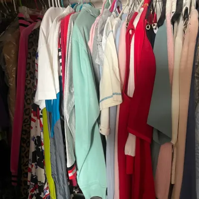 Sale Photo Thumbnail #184: Closet packed with a variety of colorful vintage and modern women's clothing items hanging on hangers.