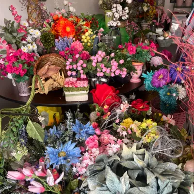 Sale Photo Thumbnail #242: Large assortment of faux floral arrangements, artificial flowers, and decorative botanical stems displayed on tables.