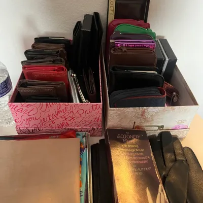 Sale Photo Thumbnail #183: Collection of assorted women's wallets, coin purses, and small accessories organized in decorative boxes alongside boxed Isotoner gloves and scarves.