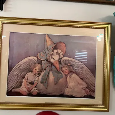 Sale Photo Thumbnail #161: Framed vintage print depicting Mother Goose flanked by two young children, presented in a ornate gold metal frame.