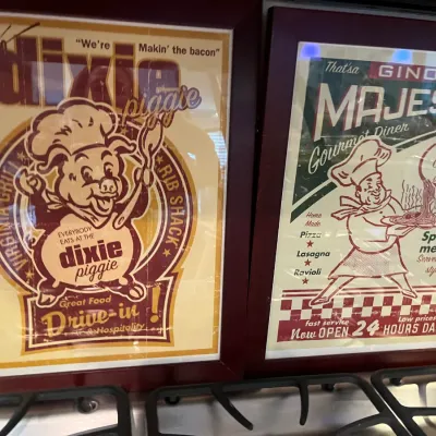 Sale Photo Thumbnail #31: Pair of framed vintage-style restaurant advertisement prints, featuring 'Dixie Piggie Drive-In' and 'Gino's Majestic Gourmet Diner' graphics.