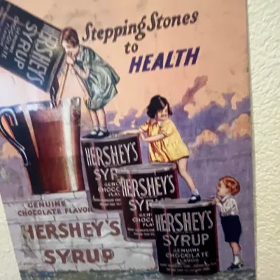 Sale Photo Thumbnail #91: Vintage-style Hershey's Syrup advertisement tin sign featuring 'Stepping Stones to Health' artwork with children and syrup cans.